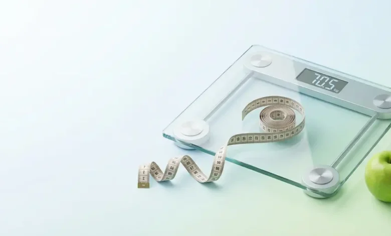 ميزان قياس الوزن وشريط قياس لحساب كتلة الجسم BMI مع رموز للغذاء الصحي.