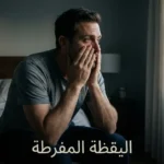 شخص يجلس على حافة سرير في إضاءة خافتة يضع يديه على رأسه بملامح مرهقة تعكس حالة اليقظة المفرطة