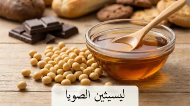 حبوب فول الصويا الذهبية بجانب وعاء زجاجي يحتوي على سائل ليسيثين بني لزج مع قطع شوكولاتة في الخلفية