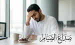 رجل عربي يعاني من صداع أثناء الصيام ويمسك رأسه بألم في مكتبه