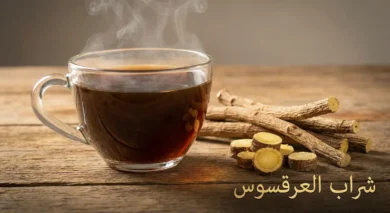 كوب شراب عرقسوس بارد بجانب جذور عرقسوس طبيعية مجففة