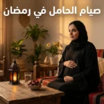 امرأة حامل عربية تجلس بسكينة أمام طاولة عليها تمر وفانوس رمضان، تضع يدها على بطنها