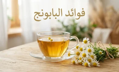 كوب شاي بابونج ذهبي اللون بجانب أزهار البابونج الطازجة على سطح خشبي مع عبارة فوائد البابونج