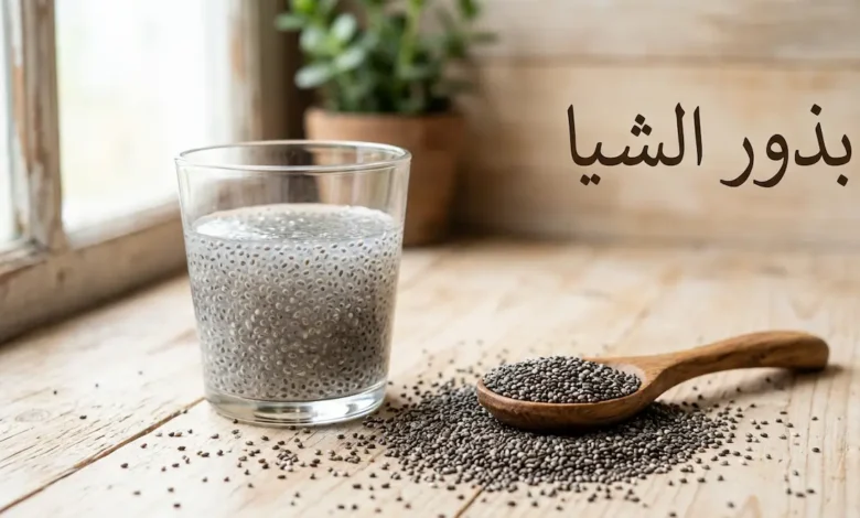 بذور الشيا مبعثرة على سطح خشبي مع ملعقة خشبية وكوب يحتوي على بذور الشيا المنقوعة المتحولة إلى مادة هلامية