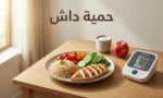 طبق طعام صحي يحتوي على أرز بني ودجاج مشوي وخضروات طازجة بجانب جهاز قياس ضغط الدم مع نص حمية داش على غلاف المقالة