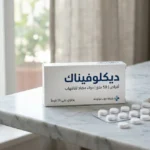 علبة دواء ديكلوفيناك مع أقراص بيضاء مرتبة على سطح رخامي في إضاءة طبيعية ناعمة