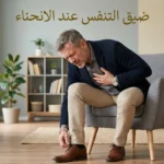 رجل في منتصف العمر ينحني لربط حذائه ويضع يده على صدره بسبب ضيق التنفس المفاجئ